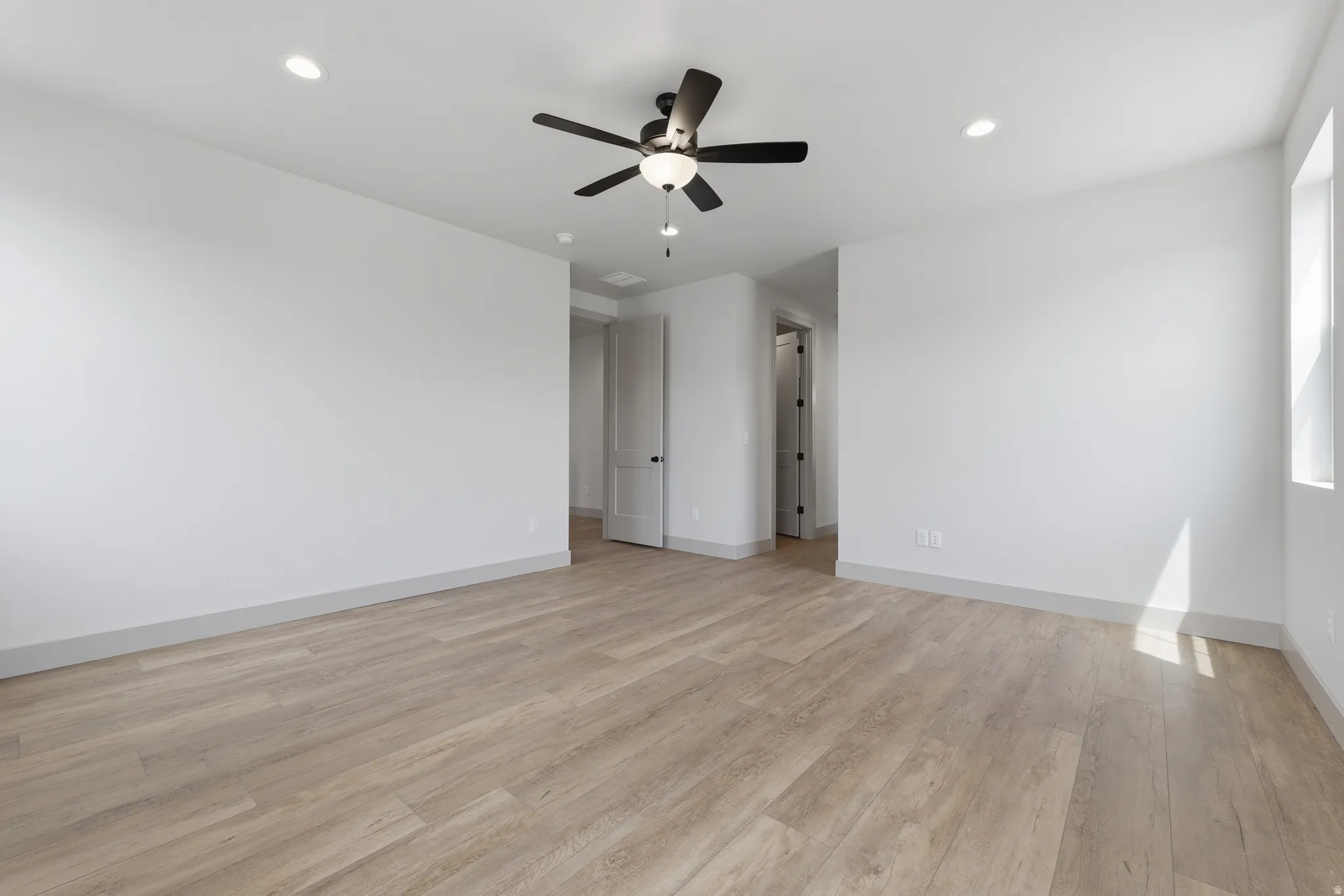 Primary Bedroom. Spacious interior room featuring wood-finish flooring, recessed lighting, and a contemporary ceiling fan with integrated light