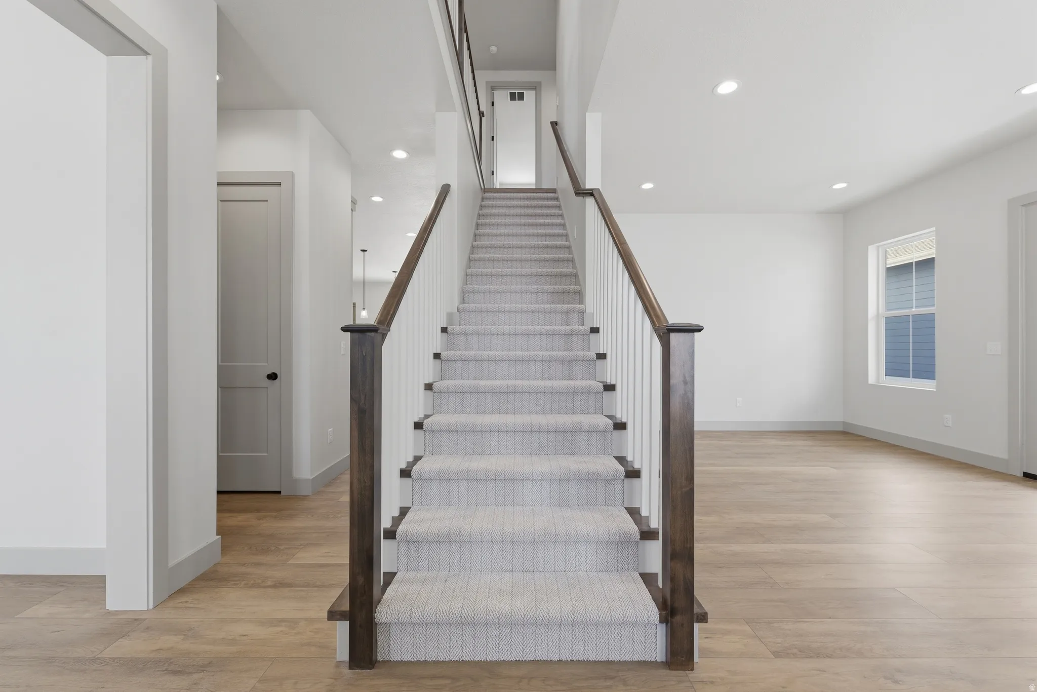 Carpeted staircase with contrasting wood newel posts and railings