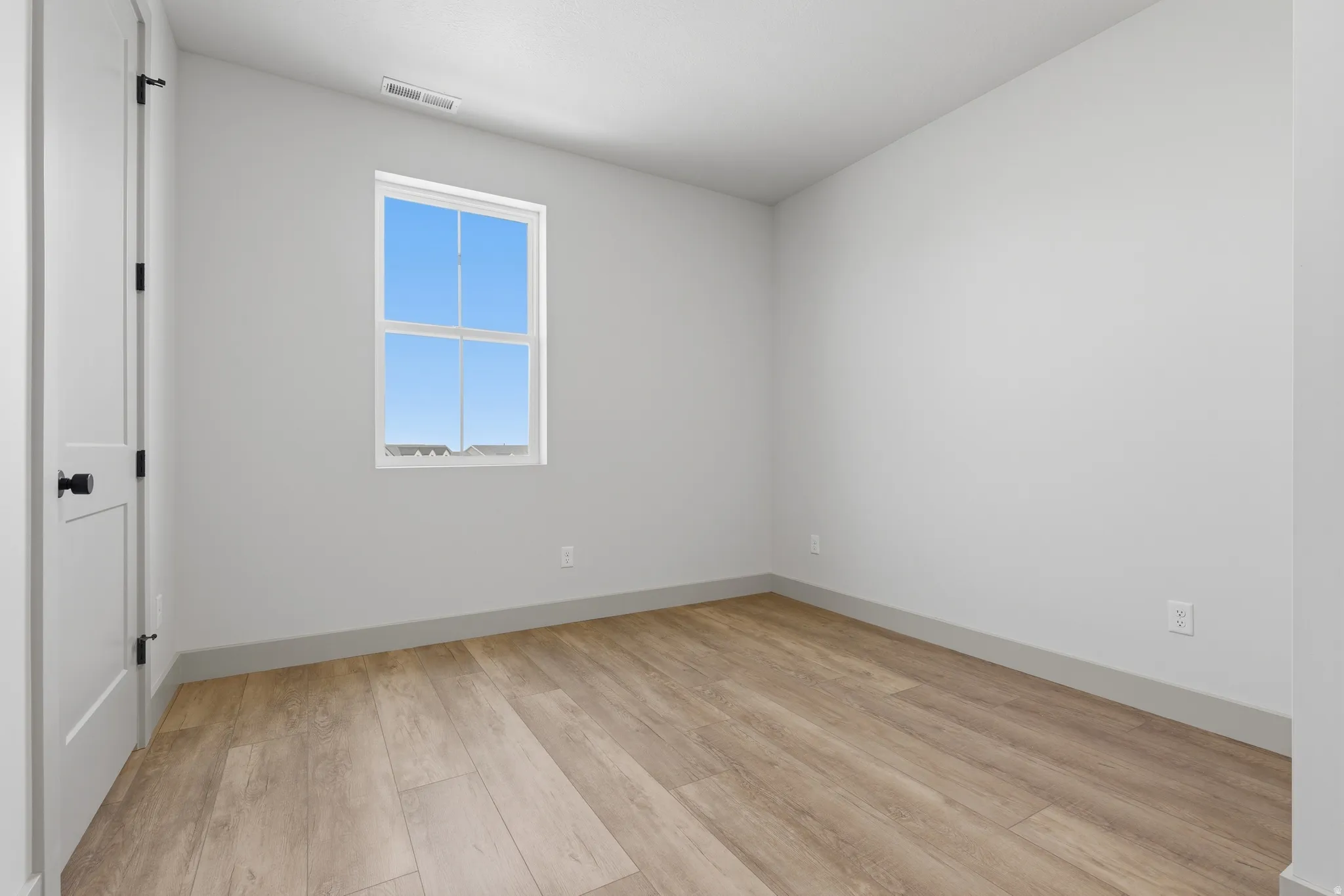 Room featuring light wood-finish flooring, neutral wall paint, and a double-hung window
