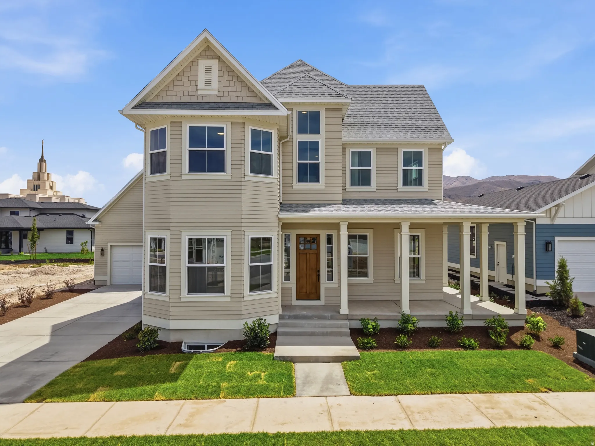 Front exterior featuring a covered porch with white columns, a natural wood entry door, and a bay window projection