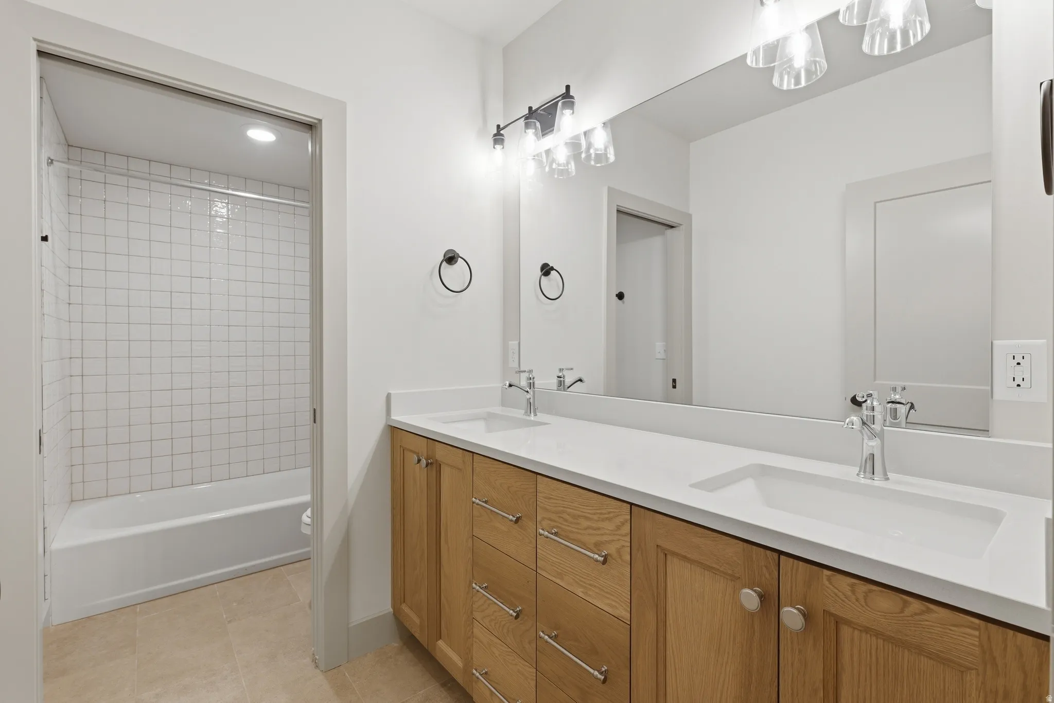 Double vanity with wood-finish cabinetry, white countertops, and chrome fixtures