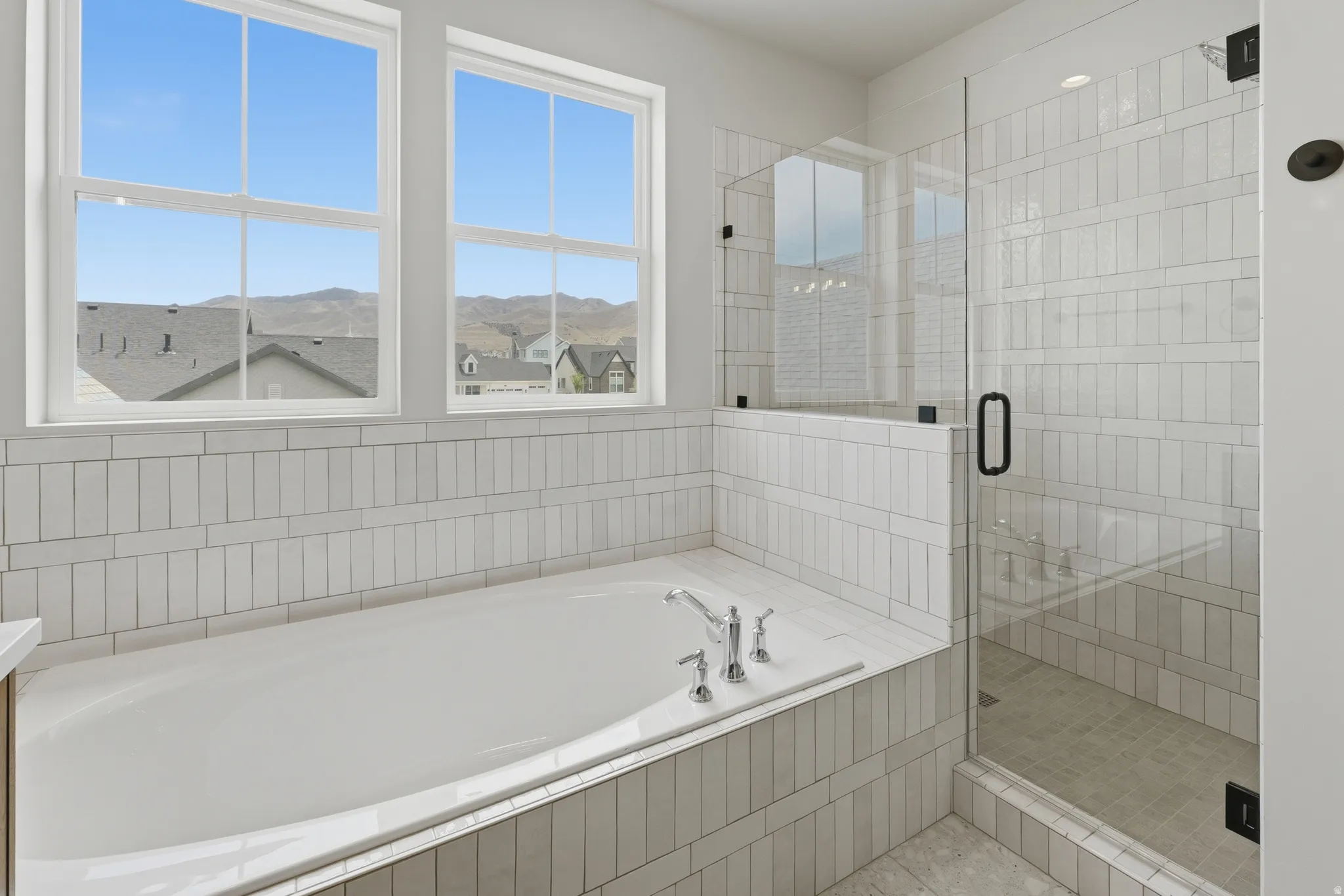 Primary Bathroom.Soaking tub with chrome fixtures, surrounded by white vertical tile