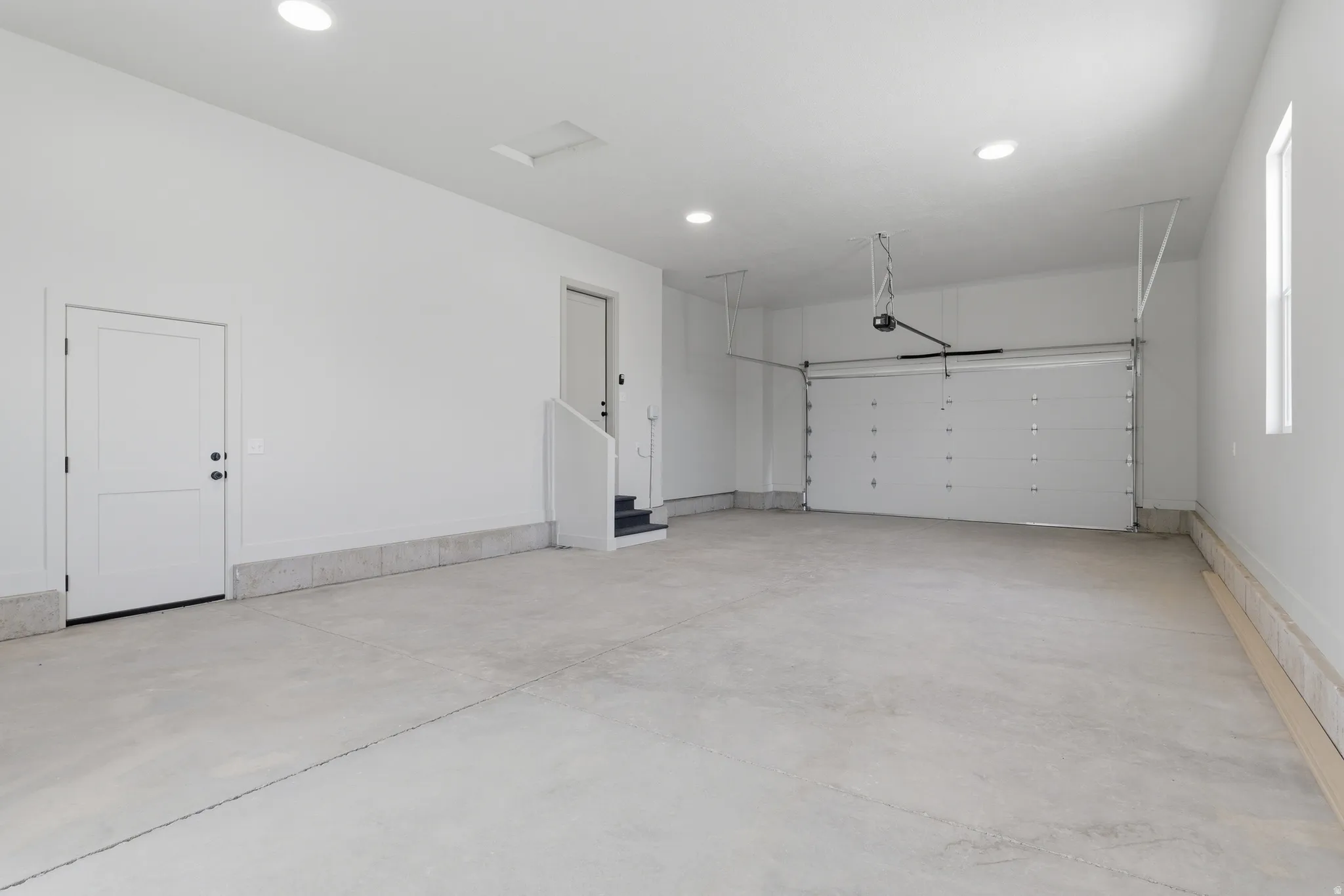 Spacious garage featuring a concrete floor, recessed lighting, and a white overhead door