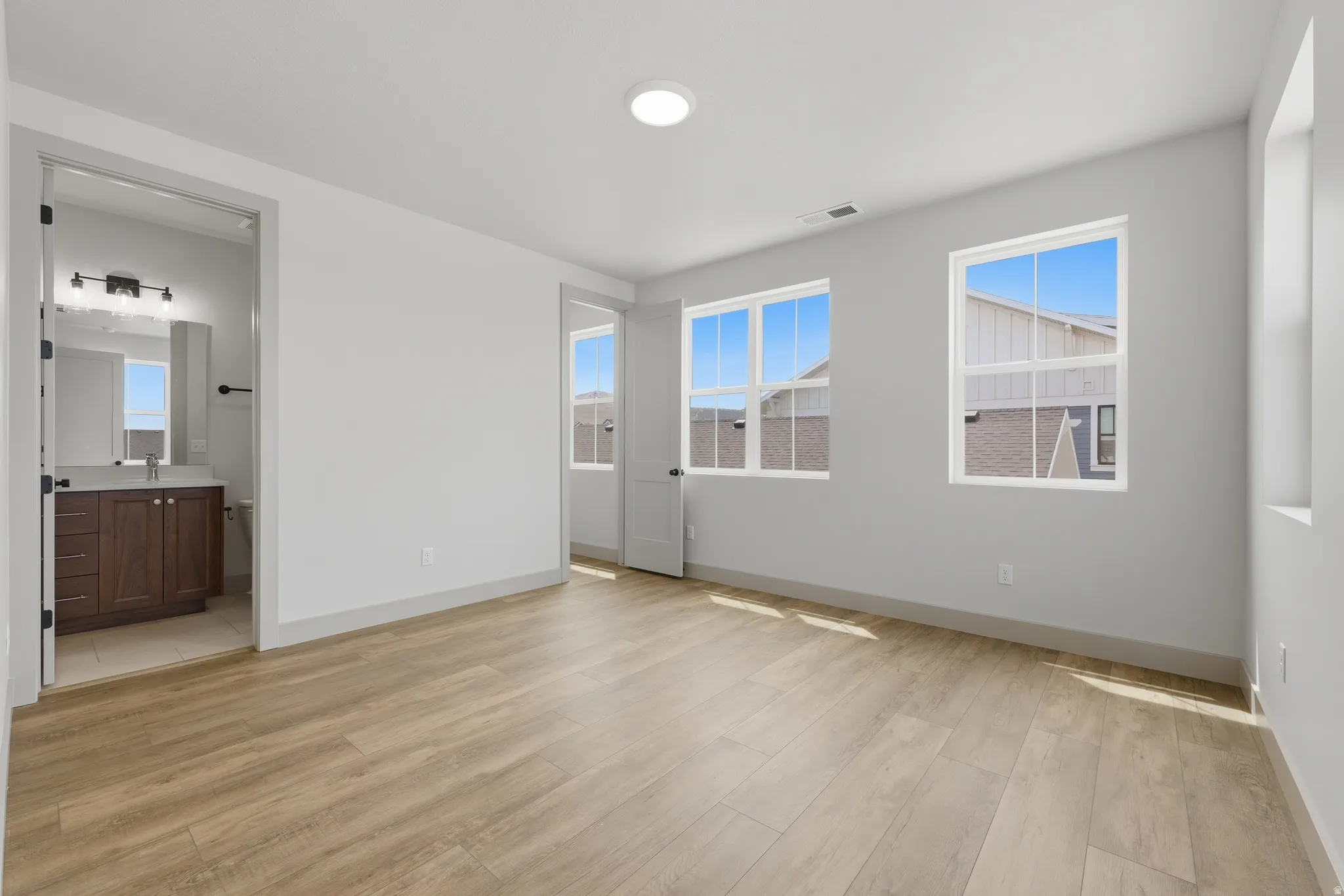 Teen Suite with ensuite bathroom. Spacious room featuring wood-finish flooring, light gray wall paint, and two large windows