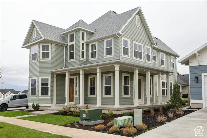 Two-story residence featuring lap siding, an expansive wrap-around covered porch with white columns, multi-gabled roofline, and numerous multi-pane windows