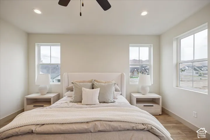 Primary Suite. Neutral interior featuring wood-finish flooring, recessed lighting, a ceiling fan, and multiple windows