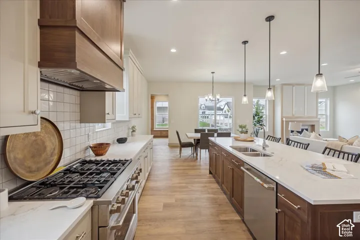 Kitchen featuring a central island with countertop seating, wood-finish cabinetry, a gas range with custom hood, stone-finish countertops, and wood-finish flooring