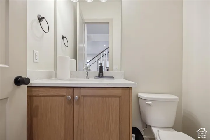 Wood-finish cabinetry featuring shaker-style doors, stone-composite countertop, integrated rectangular sink, wall-mounted mirror, and brushed-finish metal hardware