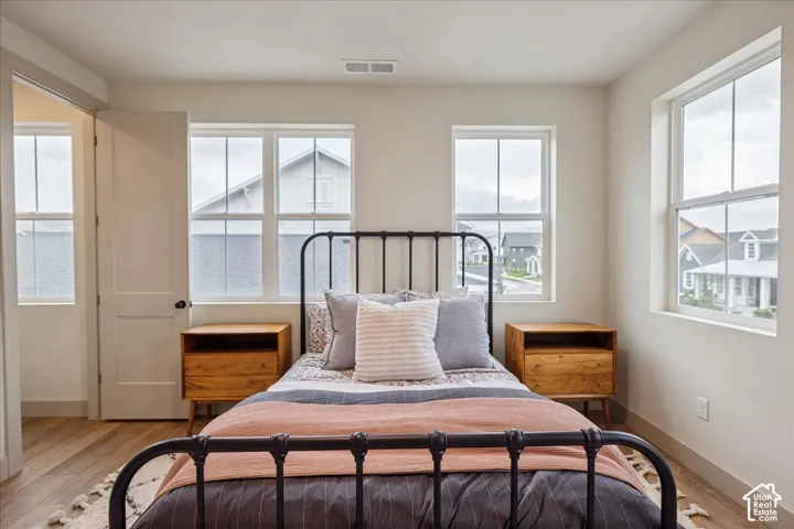 Teen suite with ensuite bathroom. Neutral-toned walls, wood-finish flooring, and multiple dual-pane windows with grid detailing