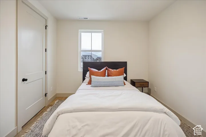 Neutral-toned room featuring a single-panel interior door with matte black hardware, wood-finish flooring, and a window with a multi-pane sash
