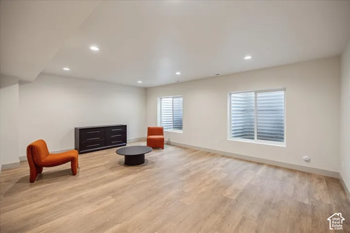 Interior space featuring wood-finish flooring, neutral wall paint, recessed lighting, and two sliding egress windows with corrugated window wells