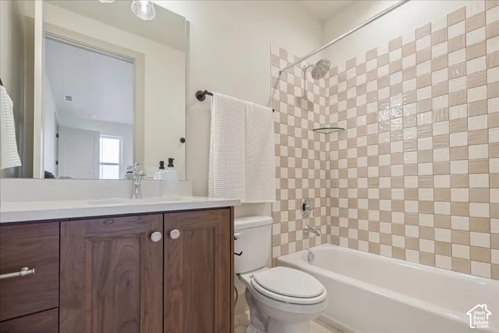 Teen suite bathroom. Bathroom featuring a wood-finish vanity with a light-toned countertop, large wall-mounted mirror, and a shower-tub combination with a checkered tile surround