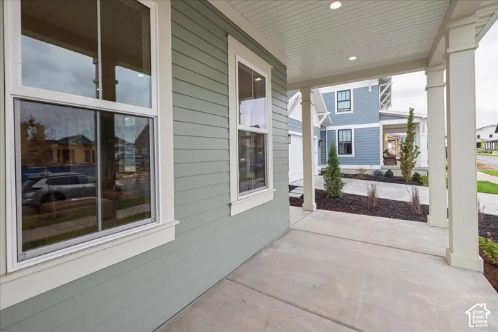 Covered porch featuring lap siding, recessed lighting, concrete flooring, and structural square columns