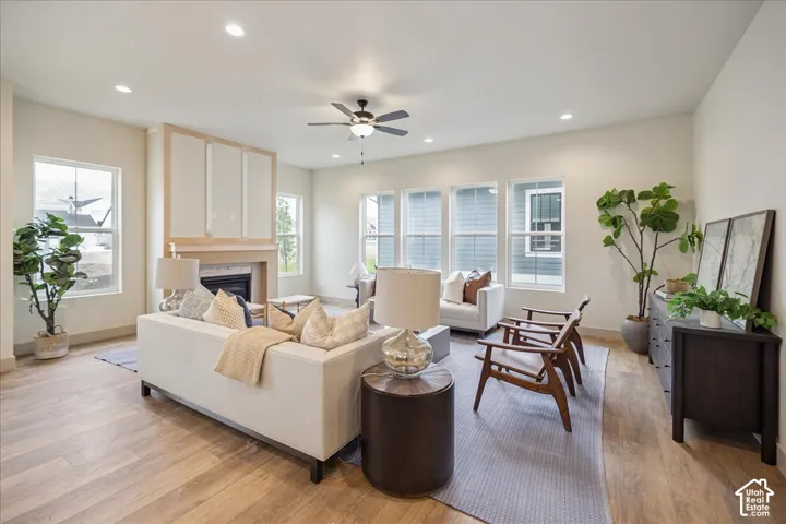 Living area featuring wood-finish flooring, recessed lighting, a ceiling fan, and a fireplace with decorative molding