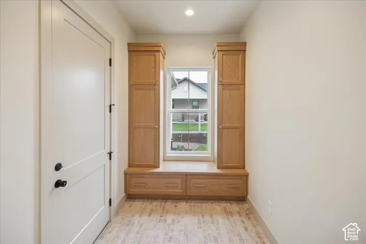 Built-in wood cabinetry with storage drawers, integrated window bench, single-hung window, solid core door with matte black hardware, and textured stone-finish flooring
