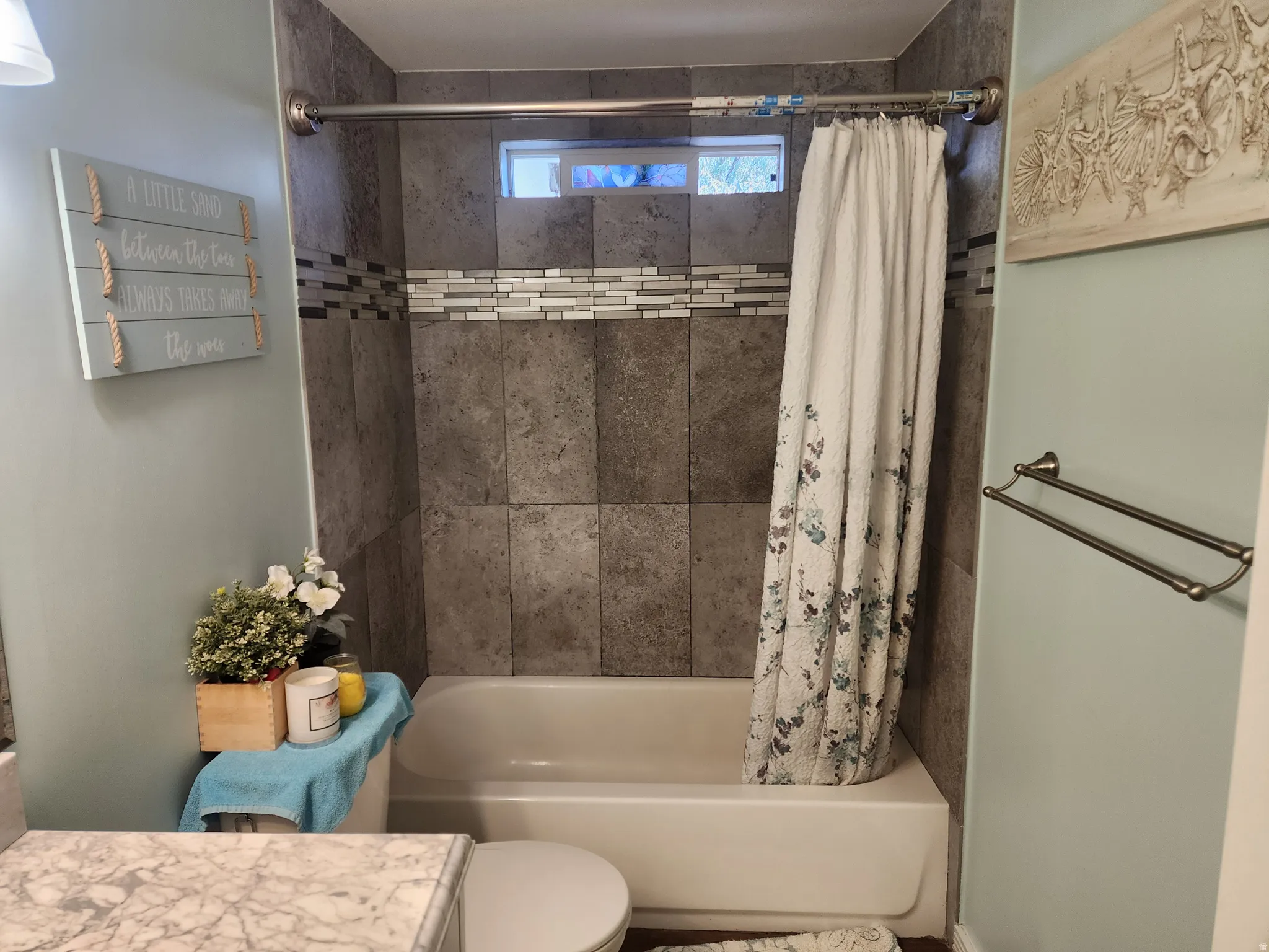Bathroom featuring a shower-tub combination with grey tile surround and decorative glass mosaic accent
