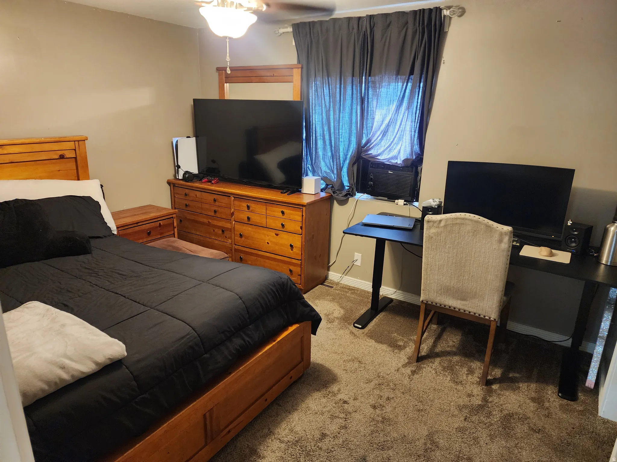 Carpeted room with a ceiling fan light fixture, window with drapes, and an air conditioning unit