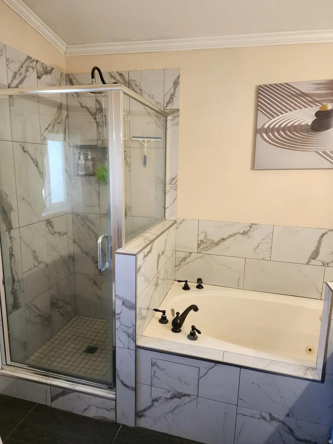 Marble-look tile shower with a glass enclosure and a built-in bathtub featuring oil-rubbed bronze fixtures