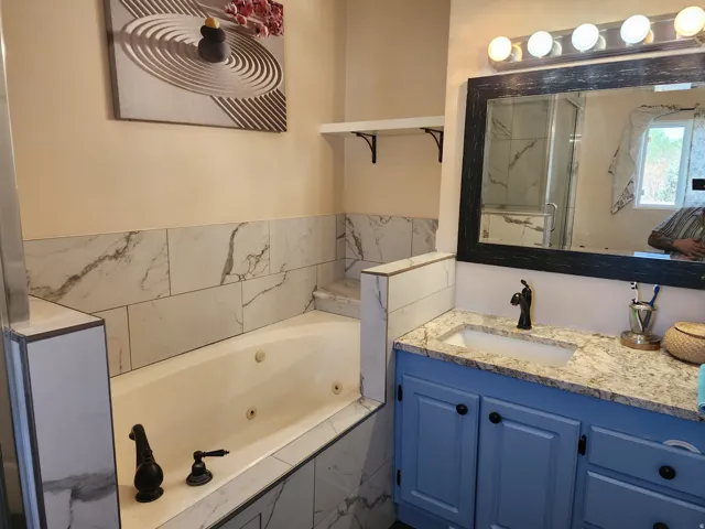 Jetted soaking tub with marble-look tile surround and deck