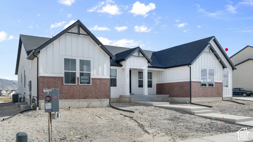 Modern farmhouse exterior with white vertical siding, dark shingle roof, and brick detailing