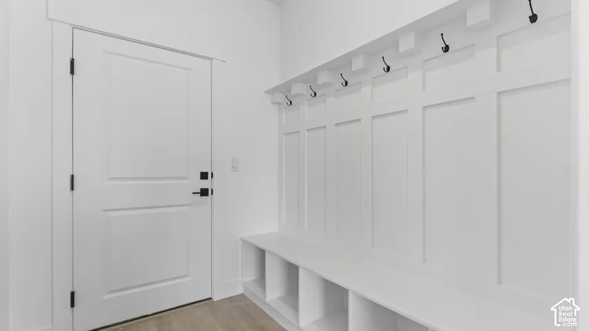 Built-in mudroom bench with cubby storage, panel accent wall, and integrated coat hooks