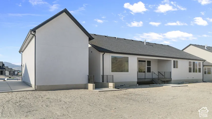 Rear exterior featuring a covered patio, multiple windows, and a dark shingle roof
