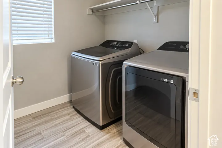 Laundry area featuring wood-finish flooring, built-in shelving, and a window with blinds