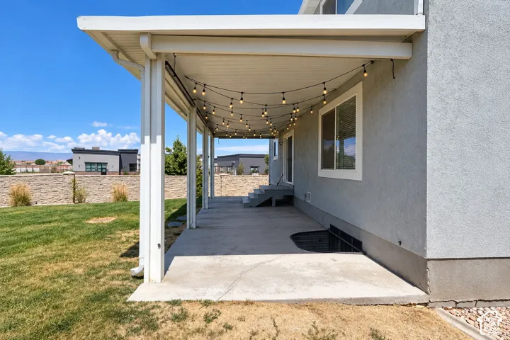 Expansive covered patio with string lighting, concrete flooring, and direct access to the exterior