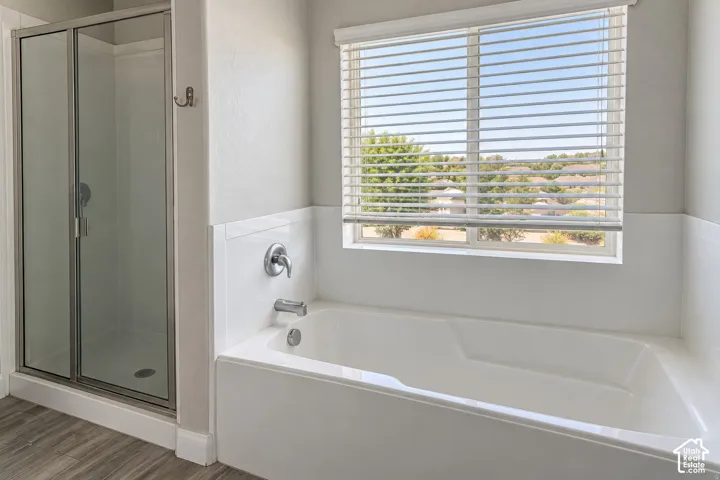 Bathtub and separate shower with glass enclosure, chrome fixtures, and a window with horizontal blinds