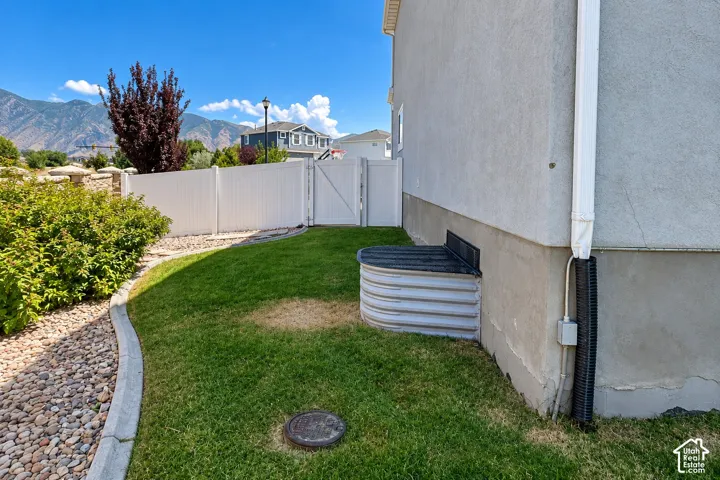 White vinyl privacy fence with gate, gravel pathway with concrete curbing, and a stucco exterior