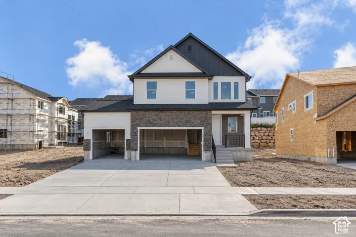 Contemporary exterior featuring a stone and siding facade, a dark shingle roof, a two-car garage, and an inviting front entry