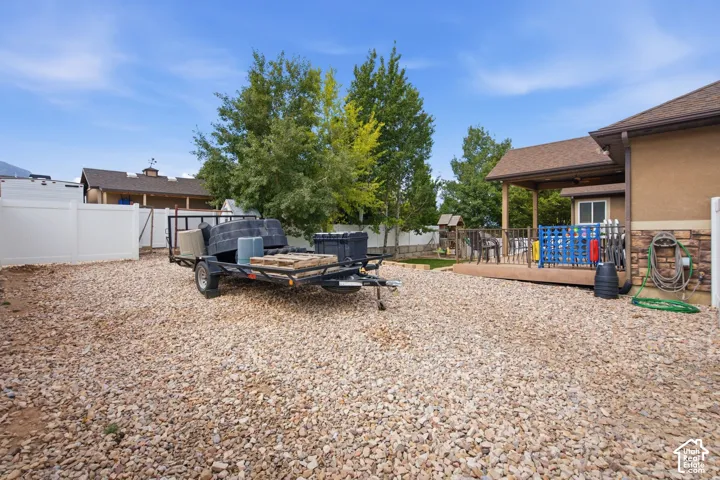Gravel yard area featuring a vinyl fence and a covered wood deck