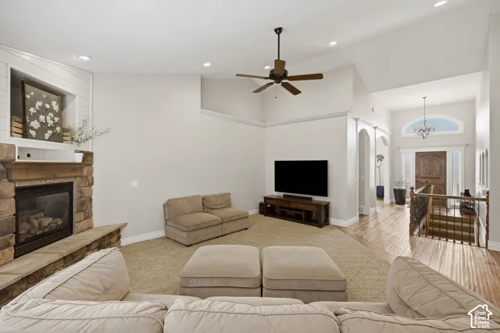 Spacious living area featuring a stone-clad fireplace with a hearth, a recessed wall niche with shiplap detailing, a ceiling fan, and recessed lighting