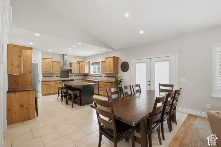 Spacious kitchen and dining area featuring light wood cabinetry, stone countertops, and a full tile backsplash