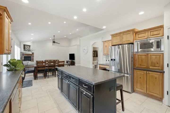 Open-concept kitchen featuring a dark countertop island with storage, stainless steel refrigerator, and built-in microwave