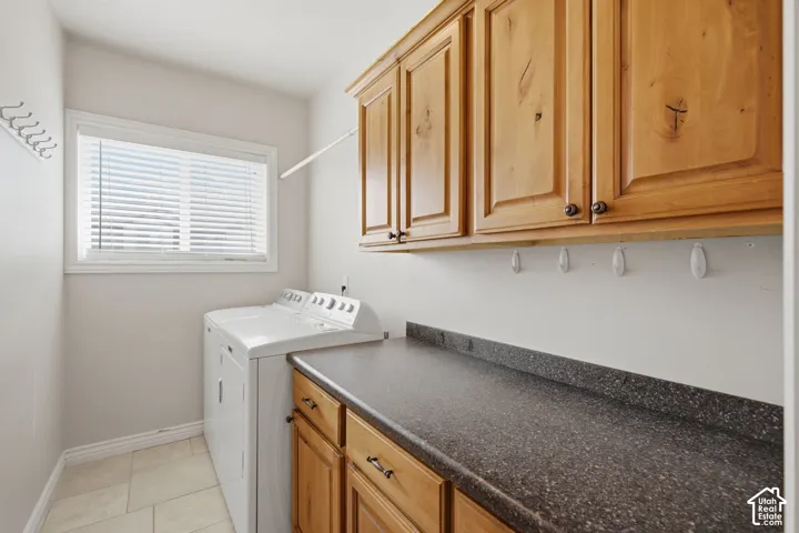 Functional utility space featuring light wood cabinetry, a speckled dark countertop, and a window for natural light