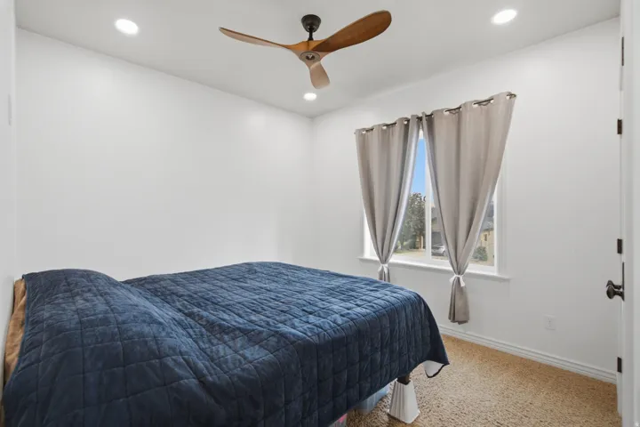 Bright interior space featuring a window with natural light, recessed lighting, and a ceiling fan with wooden blades