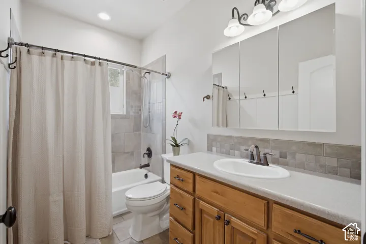 Bathroom featuring a wood-finish vanity with a light-toned countertop, an oval undermount sink with a bronze-tone faucet, a tiled backsplash, and a three-panel mirrored medicine cabinet