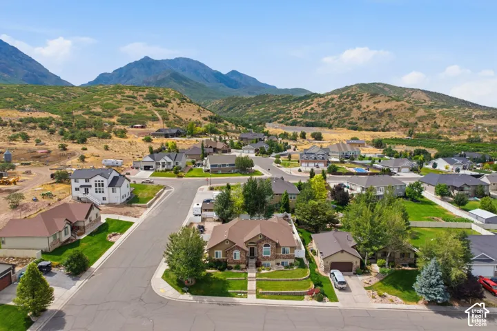 Residential neighborhood featuring paved streets and manicured lawns, set against a backdrop of rolling hills