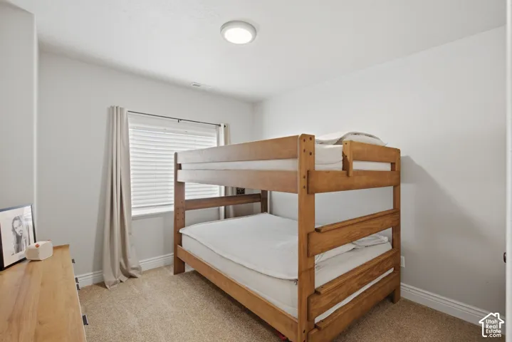Bedroom featuring neutral wall paint, light-colored carpet flooring, a window with blinds, and ceiling-mounted flush lighting