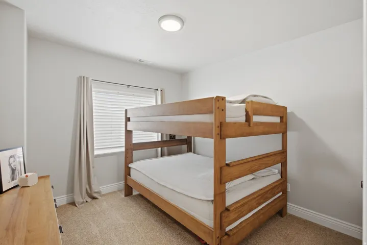 Bedroom featuring neutral wall paint, light-colored carpet flooring, a window with blinds, and ceiling-mounted flush lighting