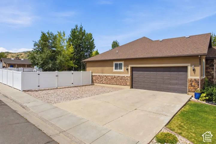 Exterior featuring stucco siding with stone accents and a brown composition shingle roof