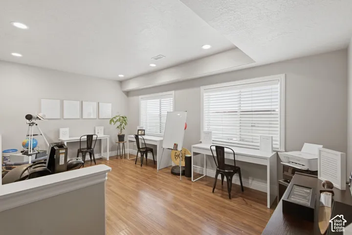 Spacious room featuring wood-finish flooring, recessed lighting, and light-toned walls