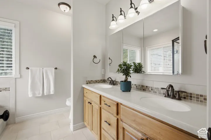 Double vanity featuring light wood cabinetry, white countertops, and dual undermount sinks