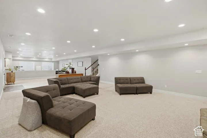 Spacious lower-level living area with recessed lighting, light-toned carpeting, and neutral wall tones