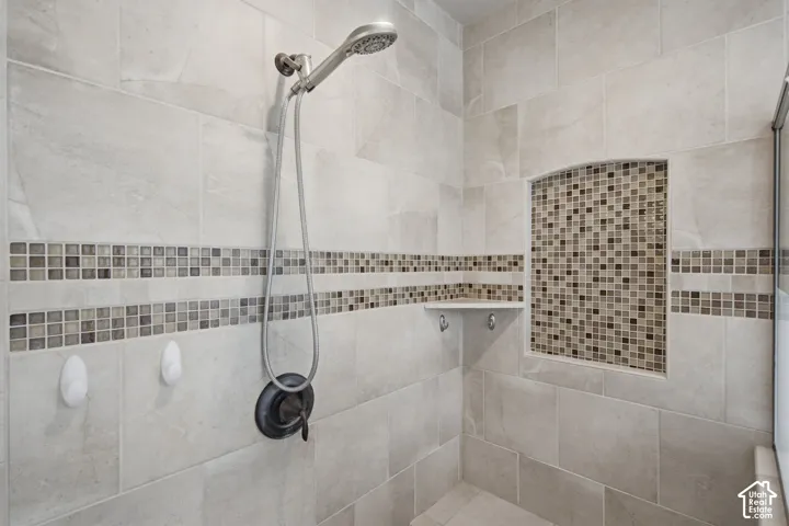 Tiled shower with a mosaic tile accent band, recessed niche with mosaic tile, and built-in corner shelf