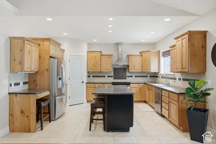 Spacious kitchen featuring light wood-finish cabinetry, a central island with dark countertop, stainless steel appliances, recessed lighting, and tile flooring