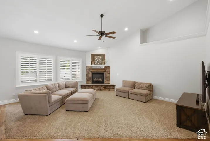 Spacious living area featuring a stone-clad fireplace with a hearth and white mantel, plantation shutters, and recessed lighting