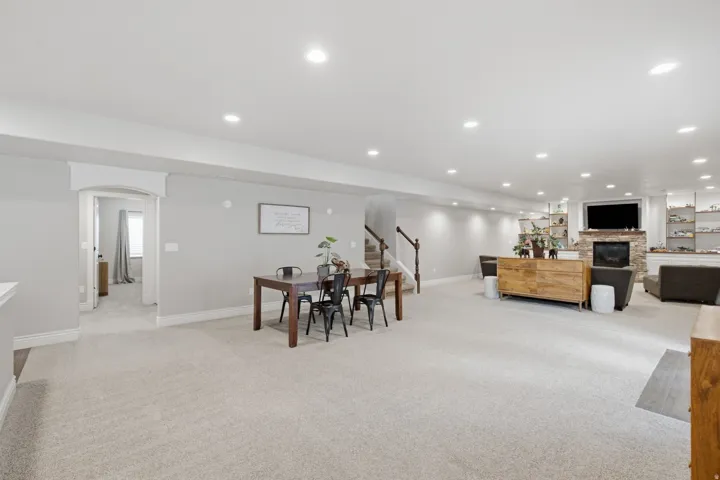 Spacious carpeted room featuring recessed lighting, a stone-faced fireplace, and built-in shelving