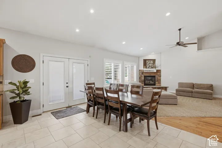 Open-concept living space with vaulted ceilings featuring recessed lighting, a stone fireplace, and a ceiling fan